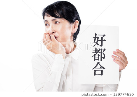 一位年長的女性手裡拿著一張寫著「贊成」的紙,笑容滿面 一位年長的女性手裡拿著一張寫著「贊成」的紙,笑容滿面 129774650