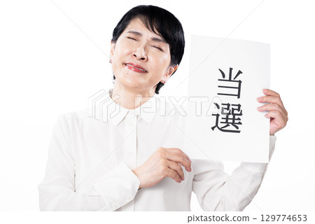 A middle-aged woman rejoicing, holding a paper that says she won A middle-aged woman rejoicing, holding a paper that says she won 129774653