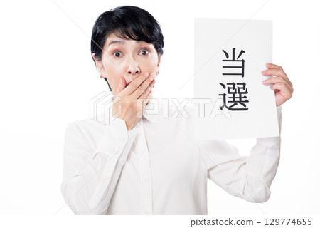 一位中年婦女很驚訝,手上拿著一張紙,上面寫著她贏了 一位中年婦女很驚訝,手上拿著一張紙,上面寫著她贏了 129774655