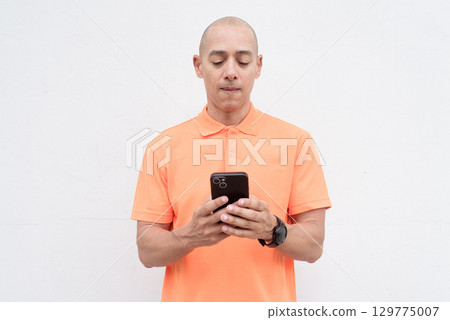 Man using internet and texting with phone against white wall background Man using internet and texting with phone against white wall background 129775007