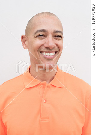 Bald Italian man face in orange polo shirt smiling and thinking 129775029