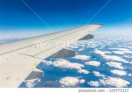 View from the airplane window at a beautiful cloudy sky and the airplane wing 129775227