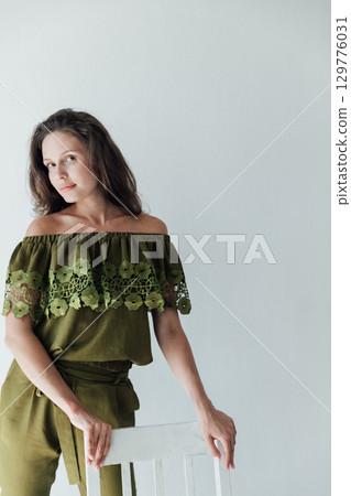 High fashion photo of a beautiful elegant young woman in a pretty juicy green jumpsuit, sneakers posing over white 129776031
