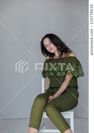 High fashion photo of a beautiful elegant young woman in a pretty juicy green jumpsuit, sneakers posing over white High fashion photo of a beautiful elegant young woman in a pretty juicy green jumpsuit, sneakers posing over white 129776038