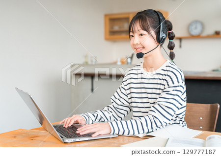 Elementary, junior high and high school students studying on a computer in the living room wearing intercoms and headsets 129777187
