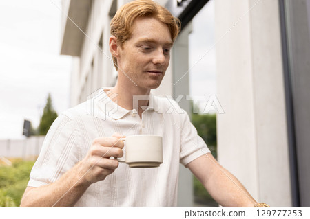 Male remote worker reviewing tasks and using laptop during breakfast 129777253