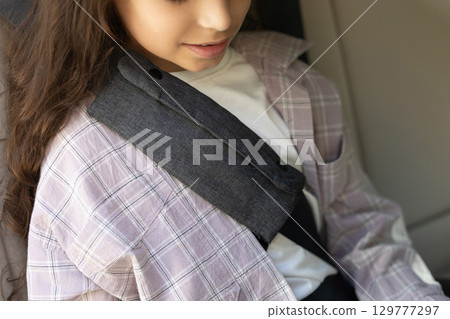 Kid sitting in a car with a fixed safety belt Kid sitting in a car with a fixed safety belt 129777297