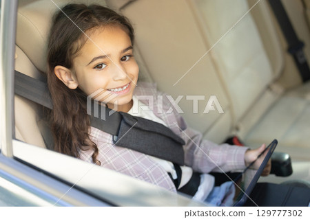Kid sitting in a car with a fixed safety belt 129777302