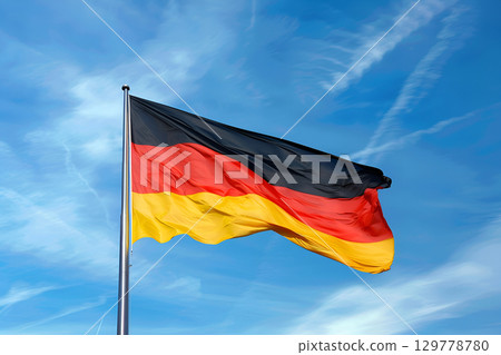 German flag waving proudly against a clear blue sky, showcasing vibrant colors of black, red, and yellow, symbolizing national pride and unity in a beautiful outdoor setting 129778780