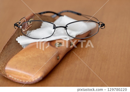 Reading glasses and a worn-out leather glasses case 129780220