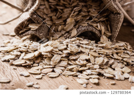 oat flakes cereal in burlap sack on wooden table. 129780364