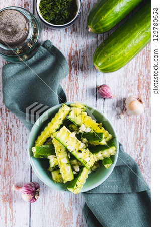 A bowl of spicy lightly salted cucumbers with herbs on the table top and vertical view A bowl of spicy lightly salted cucumbers with herbs on the table top and vertical view 129780658