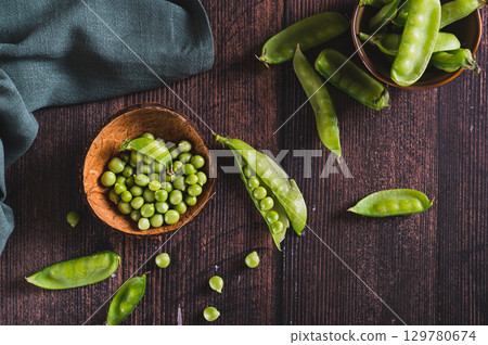 Fresh green peas in a bowl and in pods on the table top view Fresh green peas in a bowl and in pods on the table top view 129780674