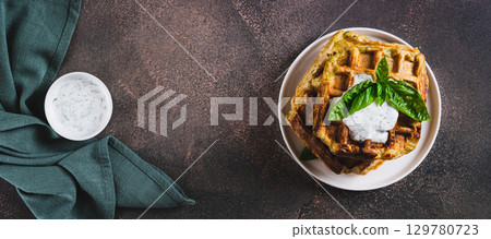 Zucchini waffles with spices, sour cream and herbs on a plate top view web banner Zucchini waffles with spices, sour cream and herbs on a plate top view web banner 129780723
