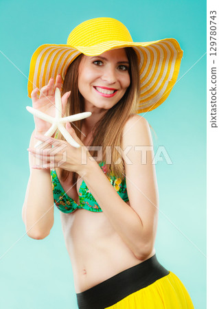 Woman in yellow hat holding white shell Woman in yellow hat holding white shell 129780743