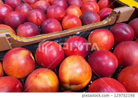Box of fresh ripe nectarines displayed at a market 129782198