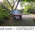 garden cleaning truck parked under lush green tree in autumn park on cobblestone path 129782207