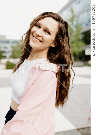 Smiling Woman Outdoors in Casual Outfit on a Sunny Day 129782208