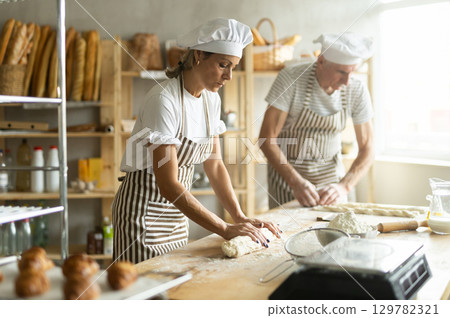 Elderly man and woman kneading and braiding dough Elderly man and woman kneading and braiding dough 129782321
