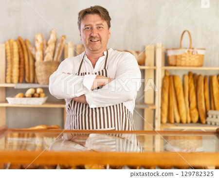 Portrait of happy professional male baker in white uniform in bakery Portrait of happy professional male baker in white uniform in bakery 129782325