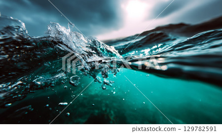 Ocean surface splash with underwater clarity and dramatic lighting from a stormy sky 129782591