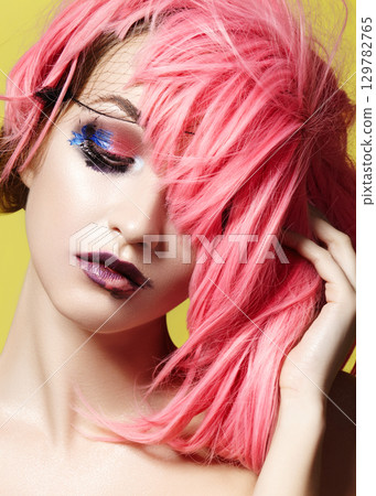 Dramatic Fashion Look young Woman in Pink Wig. Beautiful Model with bright Make-up. Carnival Accessories for Halloween Dramatic Fashion Look young Woman in Pink Wig. Beautiful Model with bright Make-up. Carnival Accessories for Halloween 129782765