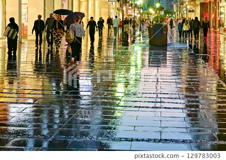 Belgrade, Serbia -- 05-25-2023: Vibrant reflections on a wet street at night in a city 129783003