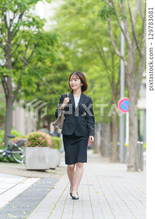 Young female business person walking outdoors 129783081
