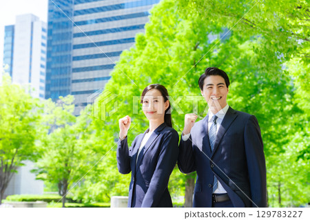 A group of male and female business people pumping their fists in a city with fresh greenery 129783227