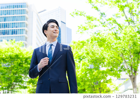 Male business person walking through the green city 129783231
