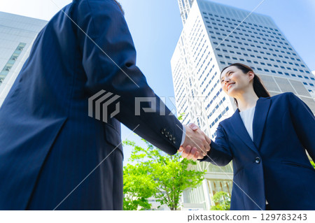 Aerial view of a group of business people shaking hands in a city with fresh greenery 129783243