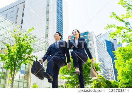 特寫:一群商務人士在綠樹成蔭的城市中跳躍 特寫:一群商務人士在綠樹成蔭的城市中跳躍 129783244