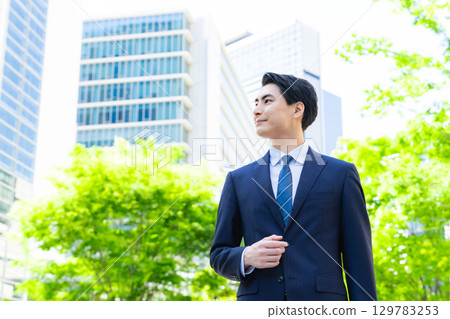 步行穿過綠色城市的男性商人 129783253