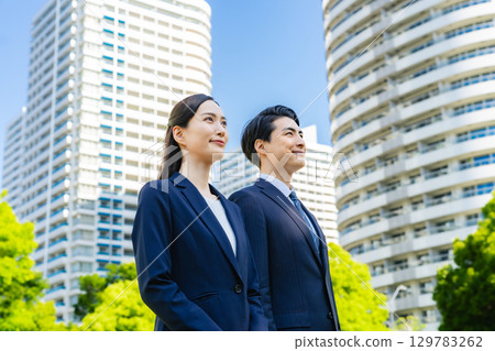 站在綠樹成蔭的城市中的男女商人 129783262