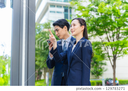 男性和女性商人透過查看地圖和智慧型手機來檢查位置 男性和女性商人透過查看地圖和智慧型手機來檢查位置 129783271