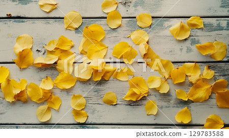 Bright yellow autumn leaves scattered on a wooden surface with natural light . Bright yellow autumn leaves scattered on a wooden surface with natural light . 129783588