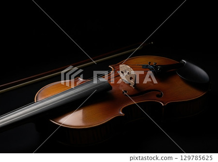 Elegant wooden violin and bow isolated on a black background in a dramatic low key studio 129785625