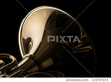 French horn with dramatic rim lighting isolated on a solid black background, close up 129785653