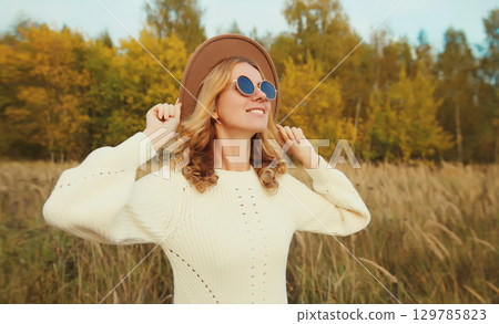 Happy young woman enjoying warm sunny weather in autumn park outdoors Happy young woman enjoying warm sunny weather in autumn park outdoors 129785823