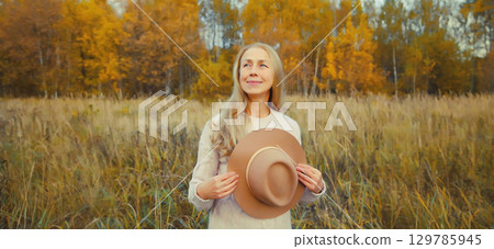 Happy smiling woman with hat enjoying warm weather in autumn park outdoors Happy smiling woman with hat enjoying warm weather in autumn park outdoors 129785945