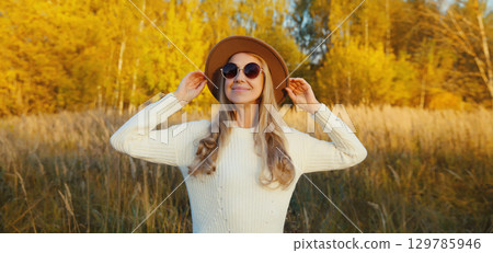 Happy young woman enjoying warm sunny weather in autumn park outdoors Happy young woman enjoying warm sunny weather in autumn park outdoors 129785946