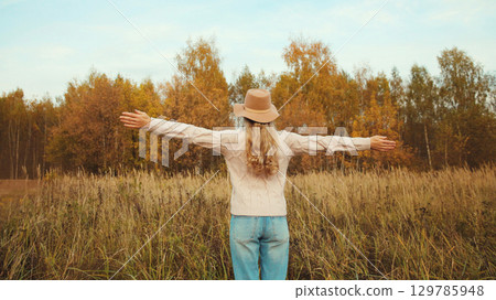 Happy young woman standing in autumn park, inspired girl enjoying warm weather, fall season Happy young woman standing in autumn park, inspired girl enjoying warm weather, fall season 129785948