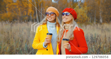 Happy two women friends with autumn yellow leaves in park, stylish smiling girlfriends together Happy two women friends with autumn yellow leaves in park, stylish smiling girlfriends together 129786058
