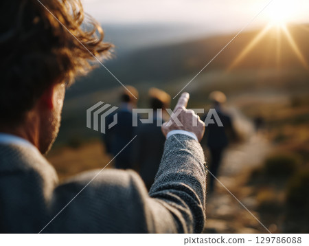 Business leader pointing toward horizon while team follows outdoor corporate retreat setting natural mountain backdrop warm Business leader pointing toward horizon while team follows outdoor corporate retreat setting natural mountain backdrop warm 129786088
