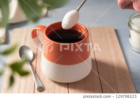 Pouring sweetener powder in cup of coffee. Sugar alternative, food and nutrition Pouring sweetener powder in cup of coffee. Sugar alternative, food and nutrition 129786223