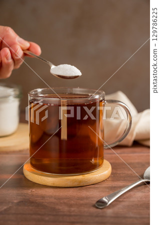 Pouring sweetener powder in cup of tea. Sugar alternative, food and nutrition 129786225