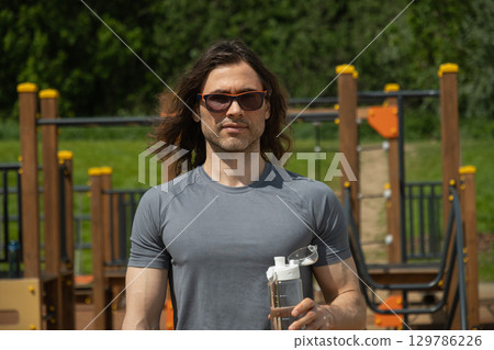 Man relaxed in park holding water bottle 129786226
