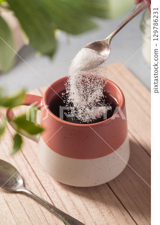 Pouring sweetener powder in cup of tea. Sugar alternative, food and nutrition Pouring sweetener powder in cup of tea. Sugar alternative, food and nutrition 129786231