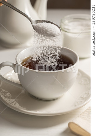 Pouring spoon of sweetener in cup of tea. Sugar alternative, food and nutrition 129786233