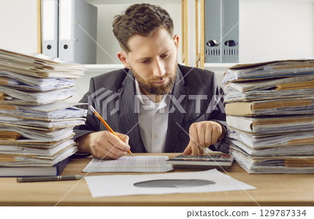 Business man working at the desk in office with a financial documents and a stack of papers. 129787334